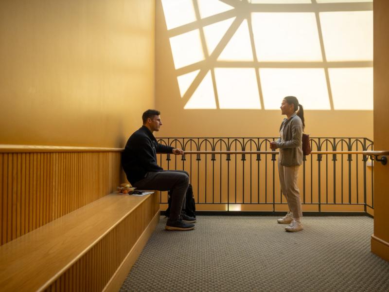 Students in the Cornell SC Johnson College of Business talk in the stairwell of Sage Hall.